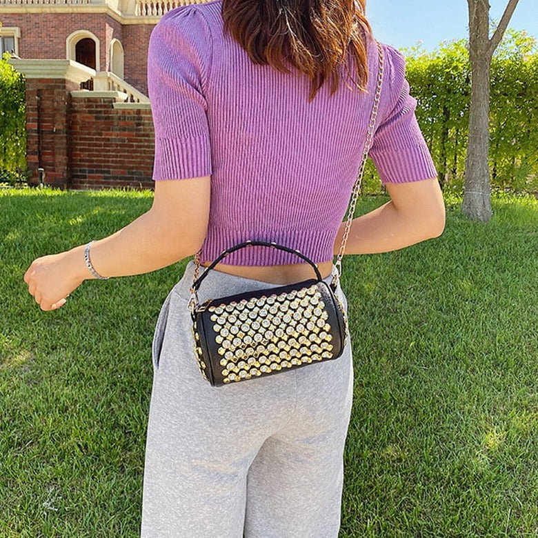 Bolso bandolera con eslogan, pedrería y tachuelas